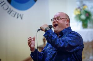 Ronan Tynan – one of the great tenor voices in the world – is returning to Medina. Tynan will perform at 7:30 p.m. on Saturday, October 5, at historic St. Mary RC Church, once again presented by the Orleans Renaissance Group, Inc. While widely known as a world-class tenor, Tynan is a much more complex and fascinating individual. His life story is as varied as the seasons, full of both tragedy and inspiring triumphs. Ronan Tynan has performed at many celebrated and historic events around the world – President Reagan’s funeral as well as the inauguration and funeral of President George H.W. Bush. His booming voice has echoed out in St. Patrick’s Cathedral, Carnegie Hall and the Washington National Cathedral; across the National Mall and at St. Peter’s Basilica at the Vatican for Pope John Paul II and Pope Benedict. Despite this incredible fame, few know the rest of his remarkable story – he is a medical doctor, Paralympian, recording artist, motivational speaker, and more. Often, it is the sum total of his life experiences that allows him to connect and bond with an audience like few other performers. Born on a farm in County Kilkenny, Ireland, Tynan was born with lower leg deformities. Despite this setback, his parents always encouraged him to do anything he wanted to do. His drive and motivation comes from the loving environment in which he was raised. His parents never let his disability stand in his way. He attended an all-boys boarding school and vigorously competed in athletic activities. A motorcycle accident at age 21 claimed both Tynan’s legs below the knee, but out of this apparent tragedy came great triumph. He went on to compete as a double amputee and win 18 gold medals and set 14 world records in the Paralympics Games from 1981 to 1984. If that were not enough, he studied medicine and became a medical doctor, specializing in orthopedic sports medicine. By the time he pondered singing, his life was already one of incredible accomplishment. When he was 30 years old, Tynan began to study voice while still in medical school. The year was 1993, and he was in his fifth year of medical school. By 1998, after establishing himself as an award-winning tenor, Dr. Tynan had joined Irish tenors Anthony Kearns and Finbar Wright and went on to legendary fame across the globe. Audiences the world over flocked to hear this trio. However, after six years, Tynan left the group to begin his solo career. Today, Tynan continues with his career, entertaining sold-out audiences in churches, theaters and concert halls around the globe. He is one of the most sought after motivational speakers in the U.S., presenting nearly 50 speeches annually for major international corporations and organizations. Before his appearance in Medina this October, Tynan will perform in New Orleans and shortly thereafter in Boston. “The 2016 concert was one of the most incredible events I have ever witnessed, most certainly in Medina,” said Chris Busch, President of ORG. “He’s a warm and friendly man – very kind and genuine. He has enormous presence. It is quite true what has been said about his ability to connect with an audience – never have I seen an audience so thrilled and so moved. I’ve attended many concert events in my life, but experiencing Ronan Tynan is very special.” At that concert event, Tynan delighted a capacity crowd of over 600 fans, many of whom traveled to Medina from across western New York and around the United States. Tynan performed for three hours, captivating the audience with his voice, his humor and personal stories of his life growing up in Ireland. One of the highlights of the evening in 2016 came as Tynan recalled a story of how he came to sing “Over the Rainbow” at a military event, honoring several Vietnam veterans. One of the vets – a retired colonel and Medal of Honor recipient – recounted how that very song inspired him and his men throughout the conflict and helped bring everyone home alive. Tynan dedicated the song to all military personnel and first responders and recognized any present in the audience. The emotionally charged performance brought the crowd to their feet with thunderous applause. “Tickets are selling quickly,” said Busch. “If you have any thought of attending this event, do not hesitate to purchase your tickets now. It will sell out. This is your chance to experience a concert event of a lifetime in a truly magnificent setting.” Tickets are $45 each ($50 at the door) and are available at online medinaalive.com. All seats are general admission. Doors open at 7 p.m. There are a limited number of specially-priced, premium front-row seats available. For premium seat information, call 590-0699.